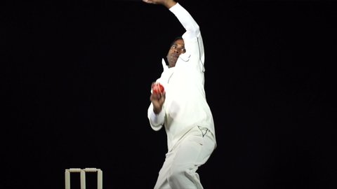 Indian Cricket Bowler bowling the ball in a game of the sport- Black background. Dressed in whites. Test Cricket