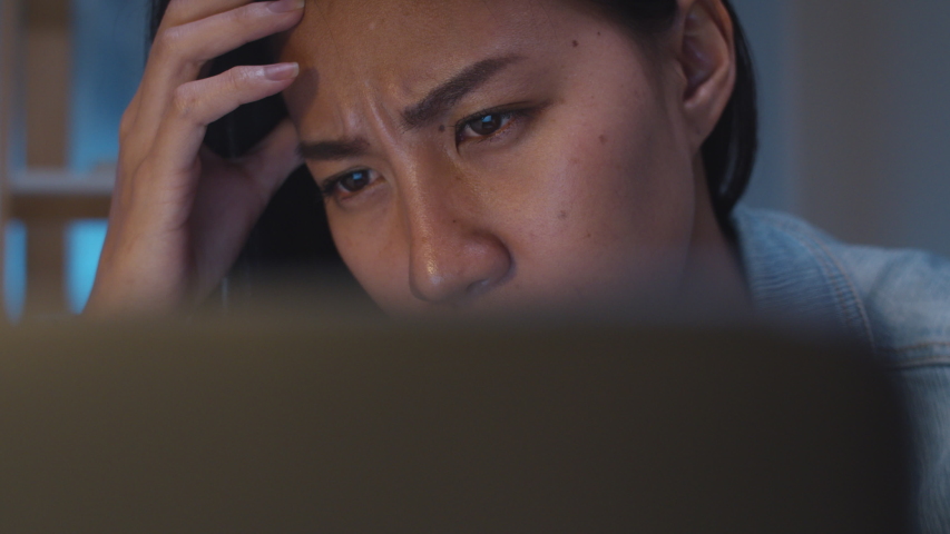Millennial young Chinese businesswoman working late night stress out with project research problem on laptop in living room at modern home. Asia people occupational burnout syndrome concept. | Shutterstock HD Video #1047326113