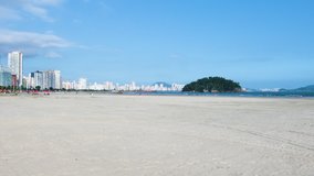 Panoramic view of a brazilian Paulista beach with a huge band of waterfront sand on beautiful day. Photo at Itarare beach, Sao Vicente city with the view to Jose Menino beach, at Santos SP city.