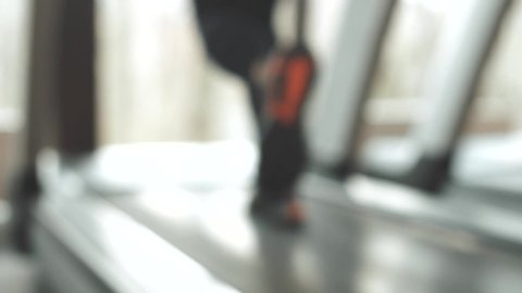 Close up blurry footage of woman running on treadmill