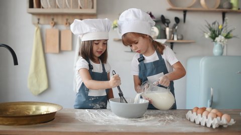 Two kids in white chef uniform mixing flour and adding milk on the kitchen. - Βίντεο στοκ