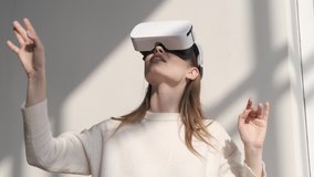 Happy cute girl using 3D virtual reality headset. Virtual reality game. Woman wearing VR headset on a white background indoors. Beautiful woman touch something using modern VR glasses - Powered by Shutterstock - Get 15% off with code: PIKWIZARD15