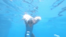 Little girl swimming in the pool, underwater view. 2.7K resolution video