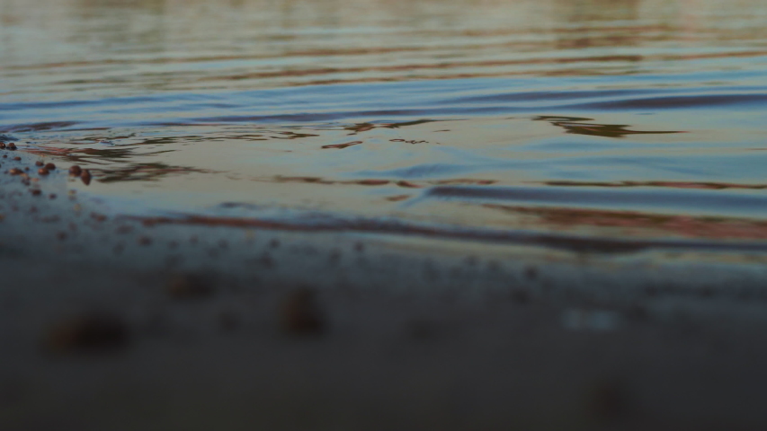 
The waves hit the shore. Riverside in sunset, sand and beach