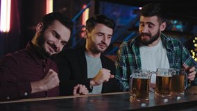 Charismatic good looking smiling large guys cheers with big glasses of beer in a pub they enjoying the time together while drinking at bar table