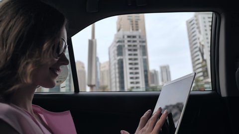 A girl in a car works with a tablet while driving in Dubai.