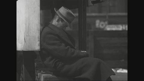 CIRCA 1930s - A man is seen sleeping on the curb of a Chicago sidewalk, while children play elsewhere in the city and another man is seen sleeping.