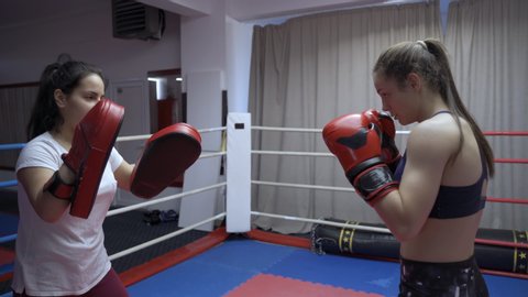 Kickboxer girl hitting mitts with her coach in the ring