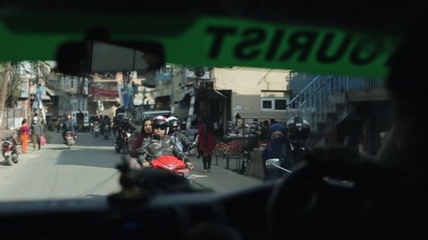 Kathmandu, Nepal - 14 November 2019: A view of a busy nepalese street from car perspective. People riding scooters, motorbikes. Traffic. Nepal Kathmandu.