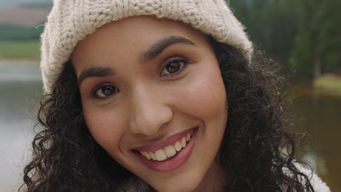 close up portrait beautiful mixed race woman smiling looking happy wearing beanie enjoying cold winter outdoors in nature by lake real people 4k