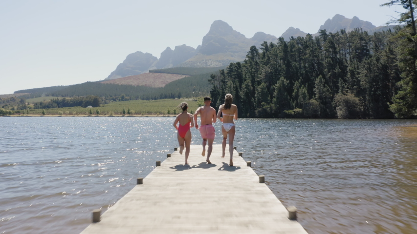 aerial view happy friends jumping off jetty in lake having fun splashing in water enjoying freedom on summer vacation overhead drone