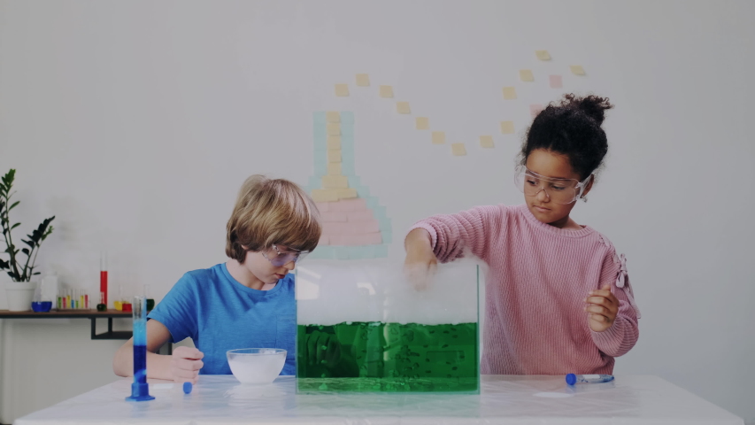 Playing with Smoke and Steam in Chemical Lab or Classroom. Clever Blond Boy and Dark-skinned Little Girl Explore Chemical Reactions in Liquid. Education, Modern Knowledge, Practice. Royalty-Free Stock Footage #1047373654