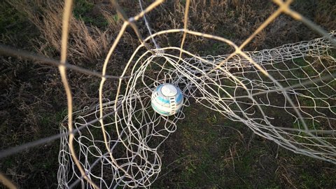 Kyiv, UKRAINE - January 2, 2020: Ball in the net. Goal. Missed ball. Losing. Football goal. The ball flies into the goal. Soccer player scores a goal. Close-up of the grid. Old football field.  