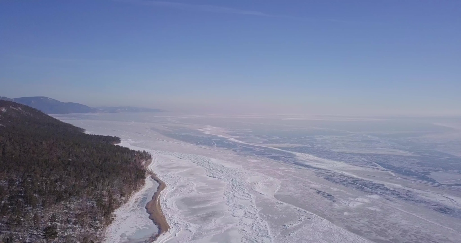 Frozen lake. Deep blue ice, hummocks, cracks Beautiful winter landscape with transparent smooth ice.
