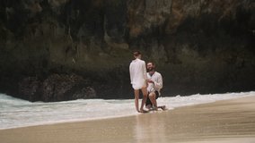 Young handsome man doing proposal to his beautiful girlfriend on empty tropical beach. Gorgeous girl saying yes to her boyfriend on paradise island. Touching moment of getting engaged couple