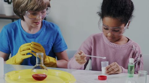 Science Research in Chemistry. Two Mix Race Kids or Pupils Makes Experiment with Chemical Reagents. Chemical volcano Rise up from Glass Flask. Learning process. Surprised Emotions.