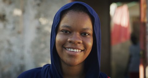 Authentic shot of an young african woman wearing burqa is smiling in camera on a background of a village. Concept: life, happiness, authenticity, religion,culture