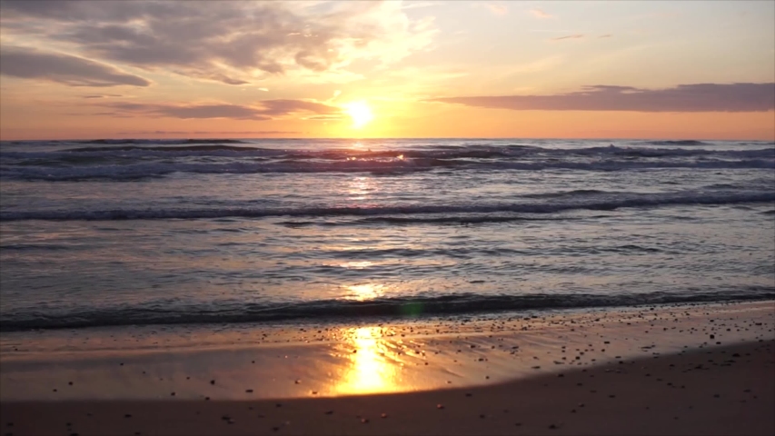 Gold Sunset Over North Sea Sand Beach in Tornby, Denmark video 4K. The sun touches horizon. Golden summer, fantastic sky, yellow sun and amazing sea. Sun go down, blue and orange clouds flow in sky. 