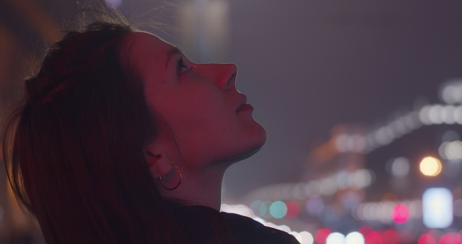 Profile portrait of Caucasian girl looking up outdoors shallow city traffic lights background copy space. Side view of young woman gazing to skies at night slow motion text. Freedom happiness dreams Royalty-Free Stock Footage #1047390931