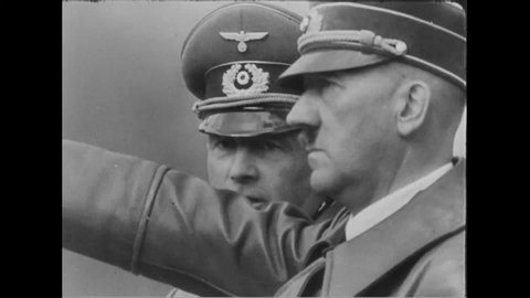 CIRCA 1940 - Hitler oversees a military parade which includes marching units, armored vehicles, and Luftwaffe planes in flight.