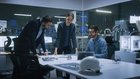 Modern Factory Office Meeting Room: Diverse Team of Engineers, Managers Talking at Conference Table, Look at Blueprints, Inspect Mechanism, Use Laptop. High-Tech Facility with CNC Machines - Powered by Shutterstock - Get 15% off with code: PIKWIZARD15