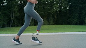 Close up handicapped athlete running on asphalt road. Fit girl training outdoors in slow motion. Young woman in sportswear doing cardio workout in park. Disabled woman running outdoors - Powered by Shutterstock - Get 15% off with code: PIKWIZARD15
