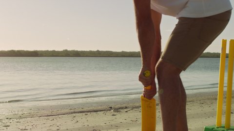 Cricket player striking ball on the beach with lake and sky in the background in Australia. Medium close on 4k RED camera.