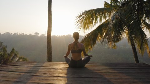 yoga woman meditating at sunrise practicing mindfulness meditation exercise sitting on deck outdoors in nature 4k