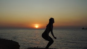 Young woman jumping up against sunset/ slow motion