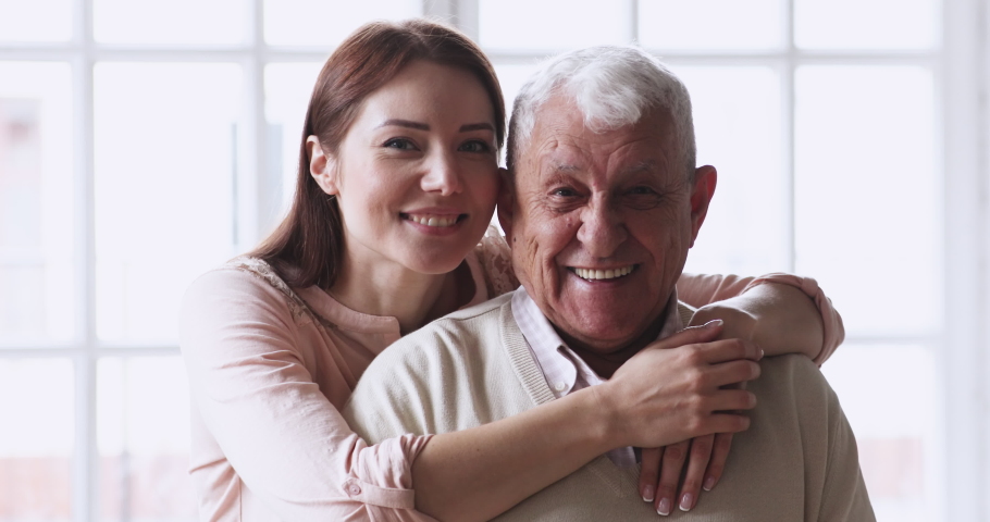 Happy caring grown granddaughter hug senior grandad cuddle look at camera. friendly 2 two age generations family old grandparent father and young adult grandchild daughter posing for close up portrait | Shutterstock HD Video #1047422596