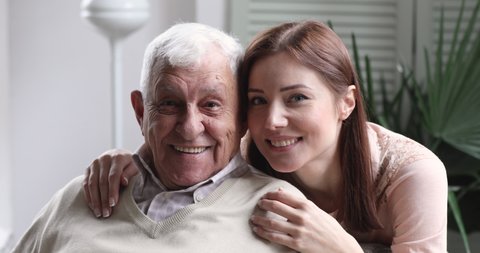 Loving smiling young adult granddaughter hug old elder grandfather at retirement home. happy grown grandchild cheerful face embrace senior grandpa bonding, close up 2 two age generation family