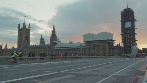 LONDON, UK- October, 20,2019 London British Parliament and Tourist People Walk on Westminster Bridge. Lamborghini is driving along the bridge. Sunset in background.