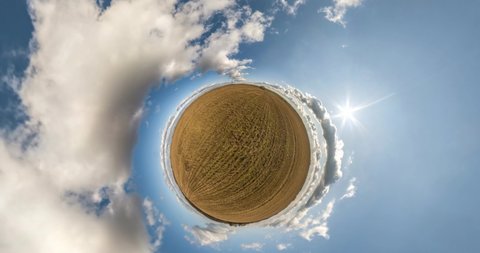 Little planet Transformation with curvature of space. Abstract rotate, torsion and spinning of full flyby panorama among fields in sunny day with clear sky and beautiful clouds