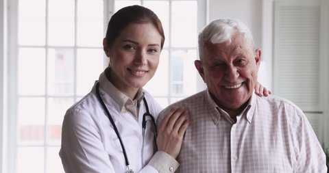 Smiling young female doctor physician wear white coat stethoscope embrace happy senior elder patient look at camera in hospital. Eldercare, old people healthcare medic service concept, close up