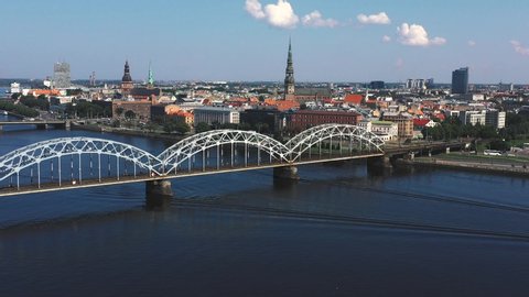 RIGA, LATVIA - MAY, 2019: Aerial video with panorama view of railroad bridge across a river and Riga city center.