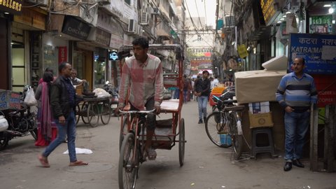 Telephoto of Dirty Street With Shops, People and Rickshaws Driving in City of Old Delhi, India - March 2019