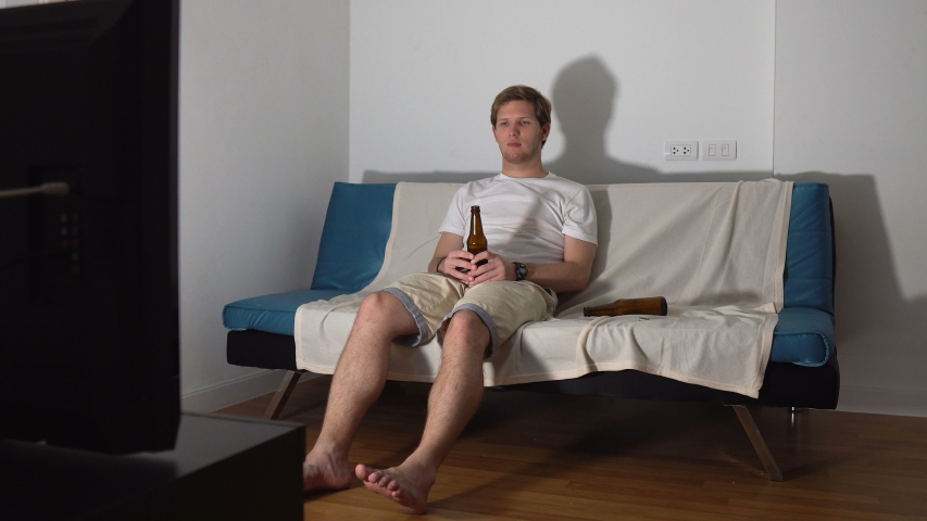 Sad Young Man Drinking Beer Alone While Watching TV at Home Royalty-Free Stock Footage #1047435493