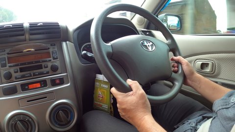 WONOSOBO, INDONESIA - FEBRUARY 27,2020: Close Up Handheld Shoot Of Asian Men Hand Is Steering And Driving A Car Behind The Wheel And Dashboard On The Right Side Of Toyota Avanza Made In Japan.