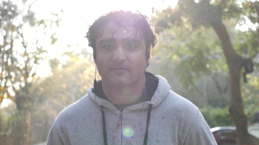 Closeup of an adult asian man wearing a hoodie sweat shirt and jogging during dawn