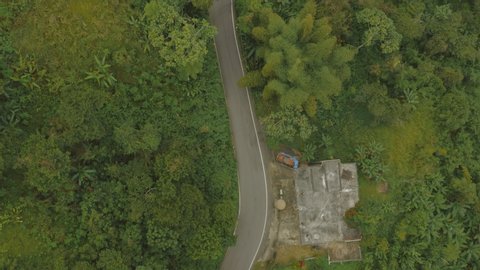 Aerial establishing shot of cars driving on a mountainous rainforest road in Puerto Rico. Cinematic 4K footage.