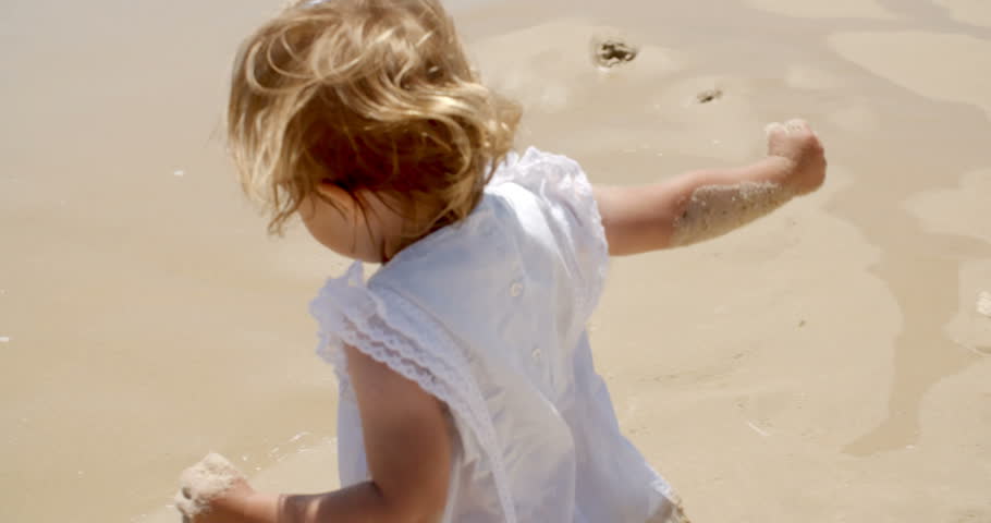 Rear View of a Little Blond Girl Enjoying the Water Splash at the Beach on a Tropical Climate During Summer.