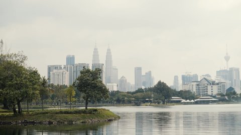 KUALA LUMPUR, MALAYSIA – JANUARY 16, 2020: Pan real time shot of Titiwangsa park and modern downtown skyline of Kuala Lumpur on background. 