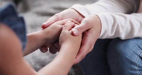 Adult mother volunteer holding hands of kid girl close up view. Foster care parent protect small child daughter give hope love care support concept. Children patient health donation charity adoption