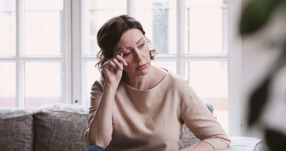Sad middle aged woman sit alone feel depressed lonely. Upset mature single lady thinking of health problem divorce solitude. 50 year old female suffer from melancholy loneliness mental disorder | Shutterstock HD Video #1047458611