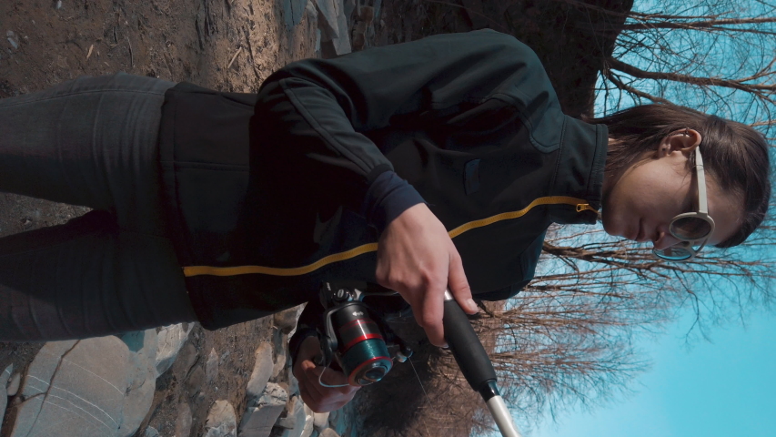 Vertical video. Portrait of fisherman woman. Girl fishing with spinning. Gender equality.