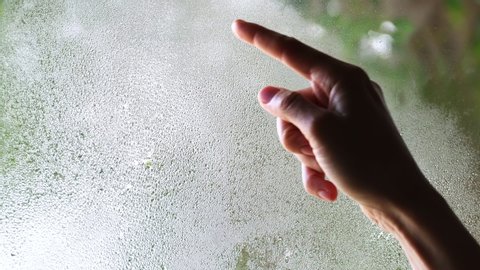 a woman's hand draws a question mark on the fogged glass. concept of the problem and its solution