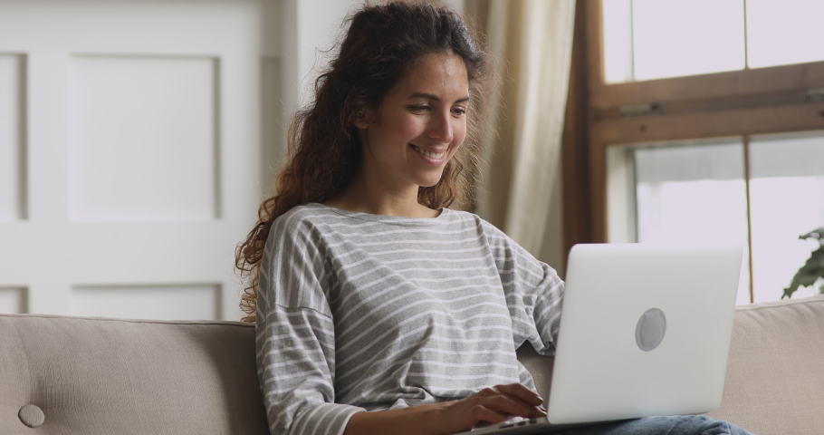 Head shot smiling pretty woman chatting with friends, using laptop. Happy young lady received promo discount code, shopping online in internet store, booking tickets, ordering food, sitting on couch. Royalty-Free Stock Footage #1047475831
