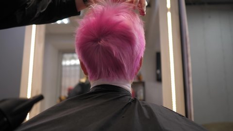 Short pink hair is blow-dried in a hair salon. Slow motion. View of the girl from behind. . 4K 50fps