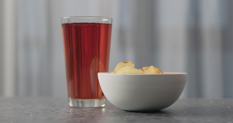 Slow motion man hand take potato chips with plack pepper from white bowl on concrtete countertop