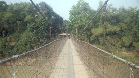 walking a suspension bridge.  Bike crossing it as backdrop ( shot from gimbal ) 